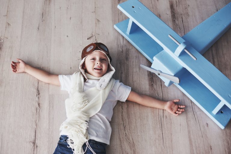 Kid having fun at home. Vintage pilot and travel concept. Top view portrait